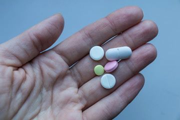 Pills on woman hand on a blue background