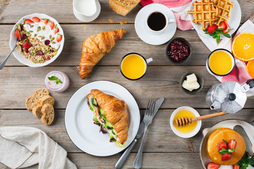 Breakfast table with waffles, granola, yogurt, pancakes, juice, coffee