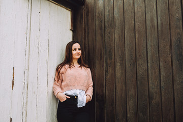 Fototapeta premium Young girl stands by a wooden wall and smiles. young girl full of life