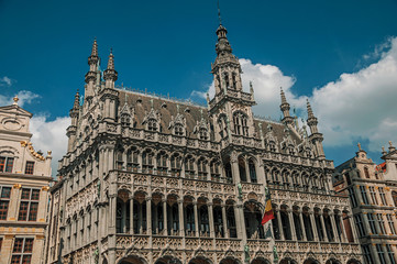 Fototapeta na wymiar Richly decorated facade in Gothic style of Brussels City Museum and Belgian flag, at Grand Place. Vibrant and friendly, is the country’s capital and administrative center of the EU. Central Belgium