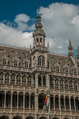 Fototapeta na wymiar Richly decorated facade in Gothic style of Brussels City Museum and Belgian flag, at Grand Place. Vibrant and friendly, is the country’s capital and administrative center of the EU. Central Belgium