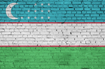 Uzbekistan flag is painted onto an old brick wall