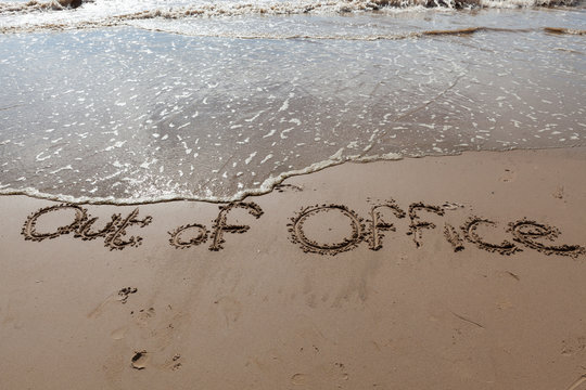 Out Of Office Written In Sand.