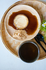 Japanese transparent mochi on wooden plate with sweet sauce, sugar and tea mug taken from top view, isolated