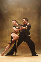 Dance ballroom couple in gold dress dancing on studio background. - obrazy, fototapety, plakaty
