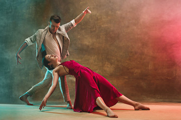 Flexible young modern dance couple posing in studio.