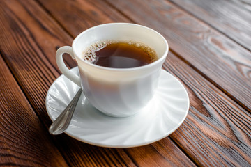 A cup of hot coffee stands on a wooden table 
