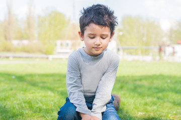 boy with his eyes lowered sits on a log