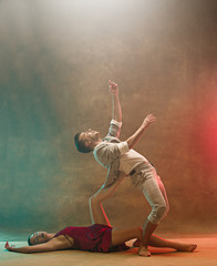 Flexible young modern dance couple posing in studio.
