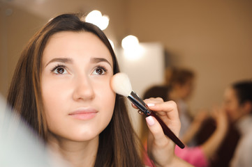 Make up artist doing professional make up of young woman. Beauty shcool.