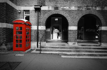 Black and white street scene with selective color on a red phone box in Sydney, Australia