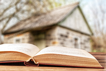 an unfolded book in the background of a summer cottage