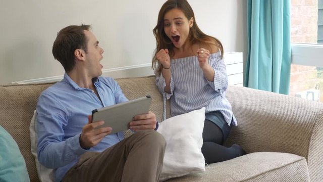 Young couple slow motion celebrating happy tablet win gambling. Slow motion static of millennial couple playing games on a tablet excitedly then winning and celebrating