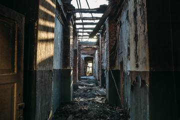 Ruins of burned brick house after fire disaster accident. Corridor inside, building without roof, heaps of ashes