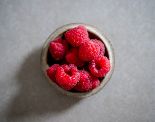 Red raspberry, in a ceramic bowl, on a gray background