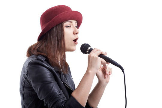 Young girl in leather hip jacket and red hat singing with microphone.