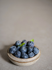 Fresh blueberries, in a ceramic bowl, on a gray background