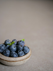 Fresh blueberries, in a ceramic bowl, on a gray background