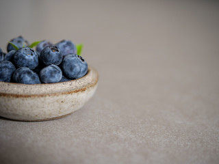 Fresh blueberries, in a ceramic bowl, on a gray background