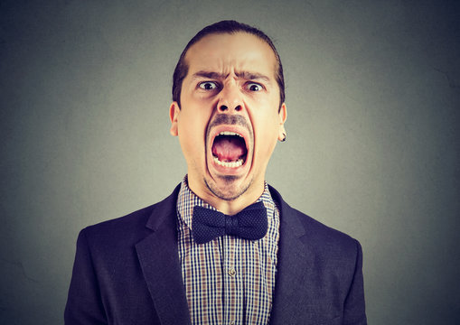 young angry man screaming with wide open mouth