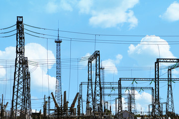 High voltage electric power station - electric poles and lines on blue cloudy sky background