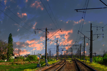 Fototapeta na wymiar Two lines railway at the country side on the sunset sky background. Electric poles at railroad.