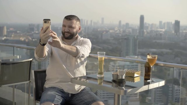 Man drinking beer and doing selfies on the rooftop
