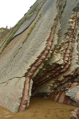 Pieces Of Pink Sandstone Wall Composed Of Fossil Records With Formations Of The Flysch Type Of The Paleocene Geopark UNESCO Basque Route. Shooting Game Of Thrones. Itzurun Beach. Geology Landscapes 