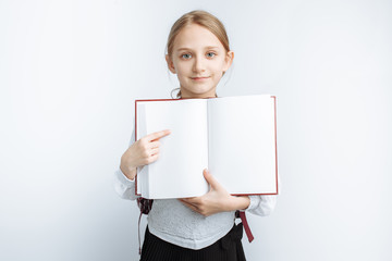 little cute girl is a schoolgirl, pointing at the book, white background, advertisement, insert text