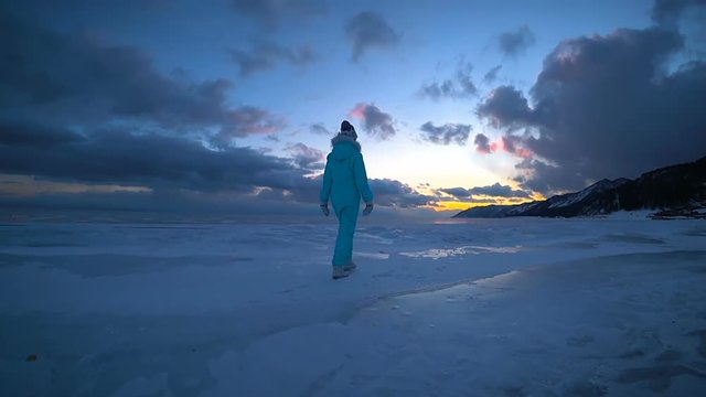 The young woman is walking on the snow on the sunset time Baikal lake Winter holiday 