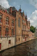Fototapeta na wymiar Old brick buildings on the canal's edge in a sunny day at Bruges. With many canals and old buildings, this graceful town is a World Heritage Site of Unesco. Northwestern Belgium.