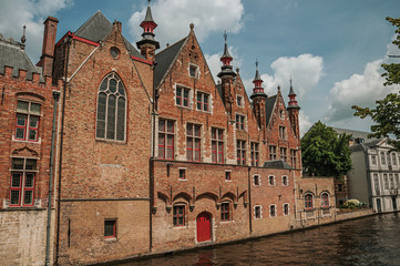 Old brick buildings on the canal's edge in a sunny day at Bruges. With many canals and old buildings, this graceful town is a World Heritage Site of Unesco. Northwestern Belgium.