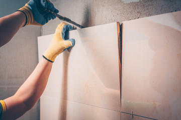 The working tiler removes the glued tile from the wall, the technology of professional and highly skilled tile work
