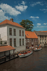 Touristic boats and old buildings on the canal's edge at Bruges. With many canals and old buildings, this graceful town is a World Heritage Site of Unesco. Northwestern Belgium. Retouched photo