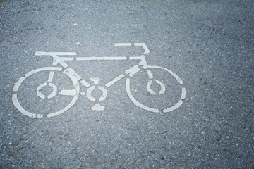Fototapeta na wymiar a white sign of bicycle way on the asphalt street at the park in city