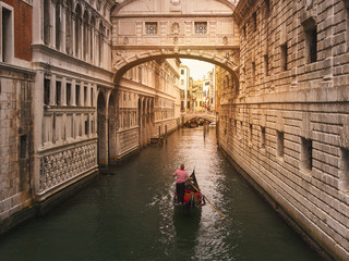 Obraz na płótnie Canvas Venecia, Italia. Gondolero llevando en su góndola a turistas, por el puente de los suspiros, durante un atardecer soleada