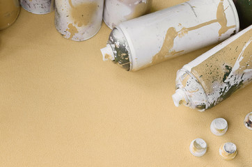 Some used orange aerosol spray cans and nozzles with paint drips lies on a blanket of soft and...