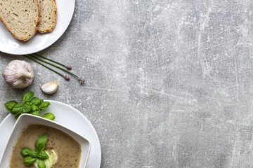 Garlic soup with bread and fresh basil on a concrete kitchen table
