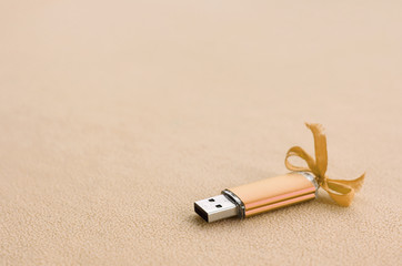 Orange usb flash memory card with a blue bow lies on a blanket of soft and furry light orange...