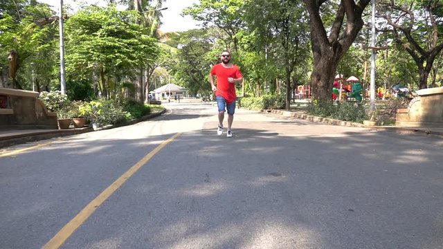 Man jogging on pavement in the park, slow motion shot at 240fps 
