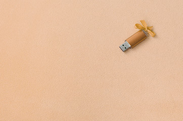 Orange usb flash memory card with a bow lies on a blanket of soft and furry light orange fleece...