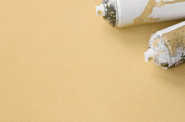 Some used orange aerosol spray cans with paint drips lies on a blanket of soft and furry light...