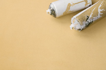 Some used orange aerosol spray cans with paint drips lies on a blanket of soft and furry light...