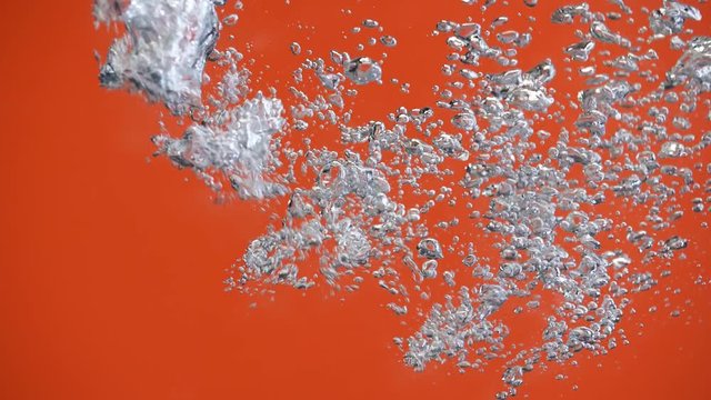 Air bubbles in the pouring water splash on orange background