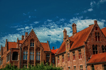Brick houses, roofs and chimneys contrasting with blue sky in Bruges. With many canals and old buildings, this graceful town is a World Heritage Site of Unesco. Northwestern Belgium. Retouched photo