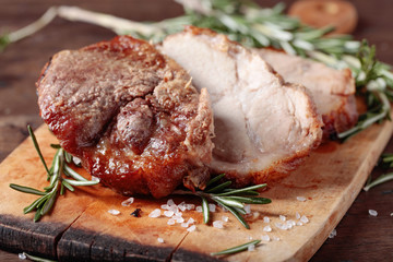 Oven-baked pork with rosemary and spices on a wooden table.