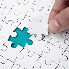The human hand fills the last missing elements of the surface from the jigsaw puzzle. The concept...