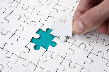 The human hand fills the last missing elements of the surface from the jigsaw puzzle. The concept...