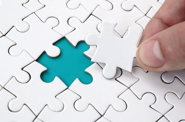 The human hand fills the last missing elements of the surface from the jigsaw puzzle. The concept...