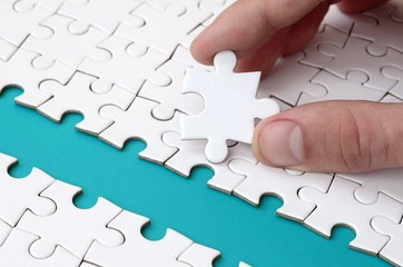 The human hand paves the way to the surface of the jigsaw puzzle, forming a blue space. The concept...